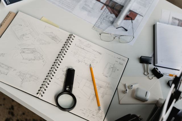 FR Diagnostics, un guide pour vendeurs, bailleurs et acquéreurs Carnet de croquis d'architecture, loupe, crayon et lunettes posés sur un bureau