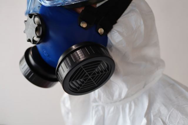 Santé et sécurité du bâti : amiante, plomb, termites, mérule Masque respiratoire à cartouches filtrantes porté avec une combinaison de protection blanche
