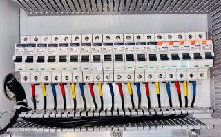 Rangée de disjoncteurs modulaires dans un tableau électrique, fils de couleur raccordés