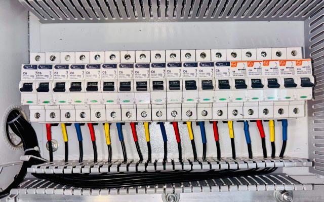 Électricité, gaz, surface et état des risques : le coût des diagnostics techniques Rangée de disjoncteurs modulaires dans un tableau électrique, fils de couleur raccordés