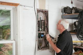 Un diagnostiqueur contrôle une installation électrique ancienne dans un appartement destiné à la location