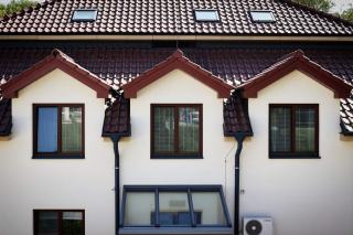 Maison blanche à toiture de tuiles percée de fenêtres de toit, unité extérieure au pied du mur