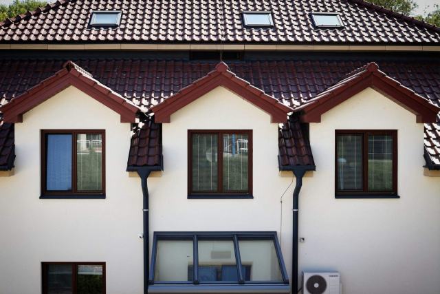 Le DPE expliqué : méthode, étiquettes, validité et annonces Maison blanche à toiture de tuiles percée de fenêtres de toit, unité extérieure au pied du mur