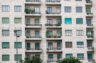 Façade d'un grand immeuble d'habitation en pierre claire, rangées de balcons fleuris