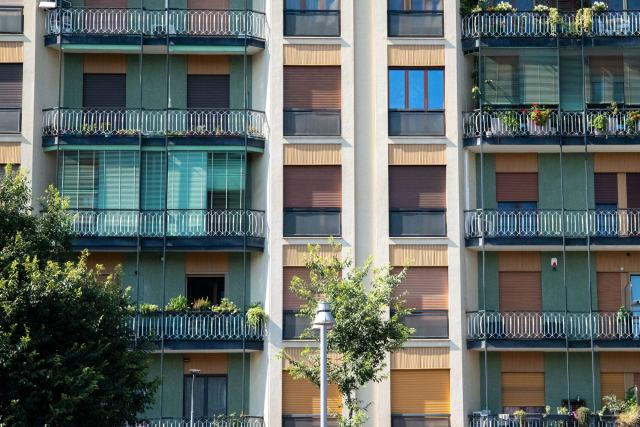 Parties communes et lot privatif : les diagnostics d'un immeuble en copropriété Façade d'immeuble en copropriété aux balcons vitrés et touches de vert, arbres devant l'entrée