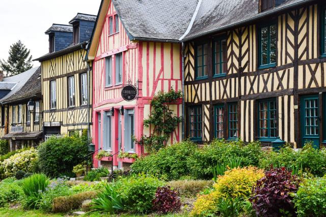 Maisons normandes à colombages roses et bruns, jardin fleuri au premier plan