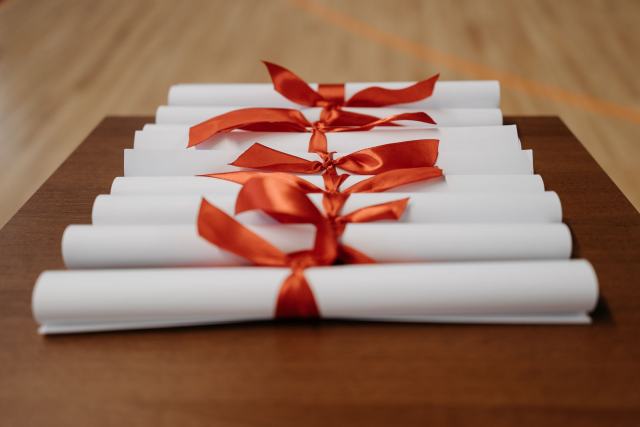 Certificats des diagnostiqueurs : domaines, mentions et contrôles Diplômes roulés et noués de rubans rouges alignés sur une table